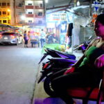 A woman sitting on a red chair in the middle of a street in Pattaya.