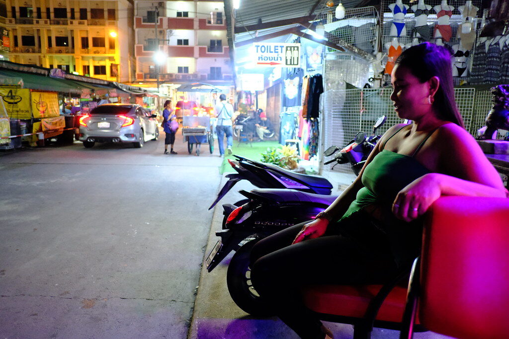 A woman sitting on a red chair in the middle of a street in Pattaya.